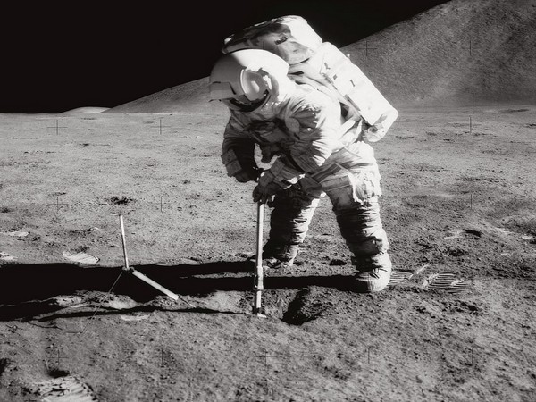 Astronaut James B. Irwin, lunar module pilot, uses a scoop in making a trench in the lunar soil during Apollo 15 extravehicular activity