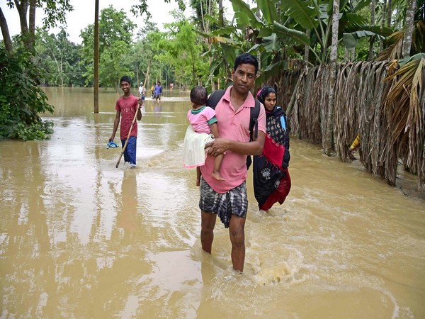 Villagers wades through a flooded area, following heavy rainfall. (Photo/ANI)