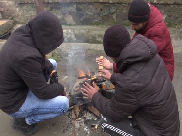 Locals in Kashmir warming hands over fire. (Photo/ANI)