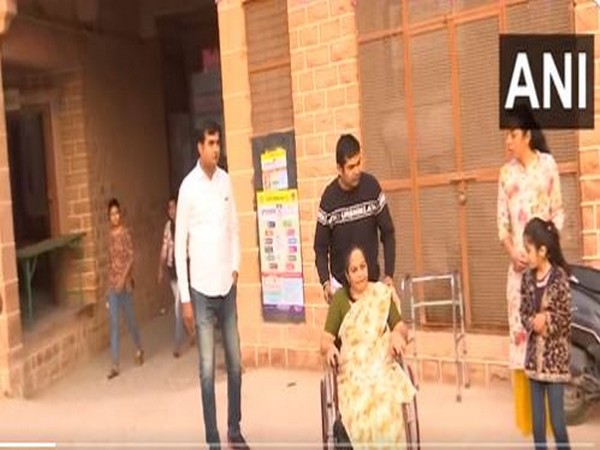 A voter on a wheelchair being helped by her family to reach the polling booth, at a polling station in Sardarpura, Jodhpur. (Photo/ ANI)