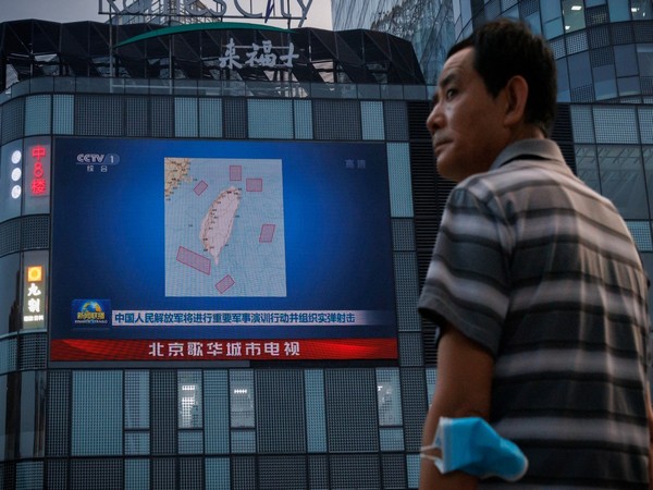 A man stands in front of a screen, showing a news broadcast about joint military operations near Taiwan by the Chinese People's Liberation Army's (PLA), in Beijing (Image Credit: Reuters)