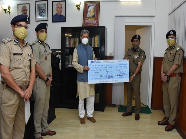 DGP Ashok Kumar giving the cheque to Chief Minister Tirath Singh Rawat