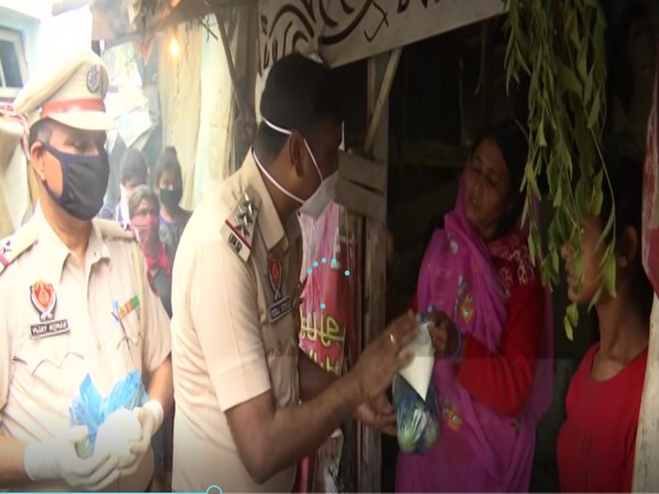 Police officials distributing free food packets to poor in Amritsar on Wednesday. [Photo/ANI]