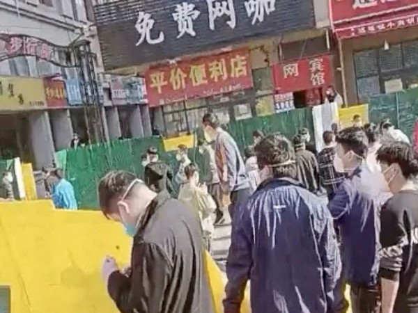 A group of people cross a downed fence following a protest at Foxconn's plant in Zhengzhou, China (Screen Grab from Reuters' videos)
