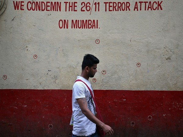 A man walks past a wall riddled with bullet holes opposite to the Nariman House, one of the targets of the November 26, 2008 attacks, in Mumbai. (Photo Credit: Reuters)