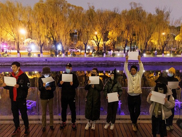 People gather for a vigil and hold white sheets of paper in protest over COVID-19 restrictions in Beijing, November 27, 2022. (Photo Credit: REUTERS)