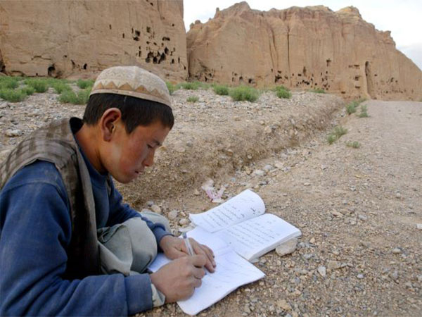A teenager of Afghanistan's Haraza community studies near the remains of the Buddhist statues at Bamyan. (Photo Credit - Reuters)
