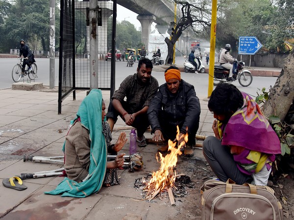 People sitting near a fire to protest from intense cold wave and dense fog in New Delhi. (ANI/photo)