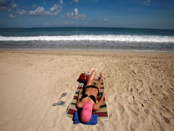 A tourist sunbathes at Kuta beach of the Indonesia's resort island of Bali. (Photo Credit - Reuters)