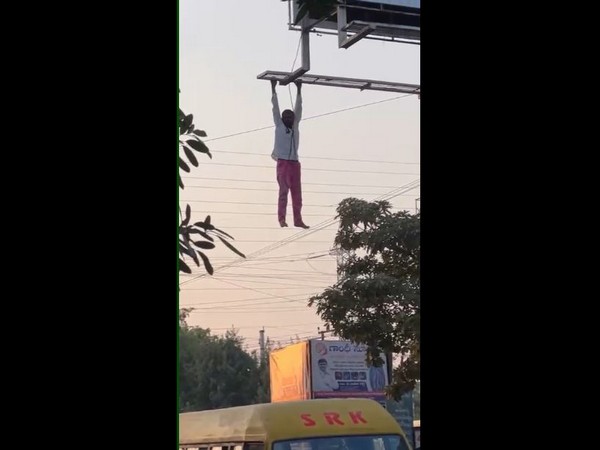 Visual of a man hanging from billboard frame in Siddipet.