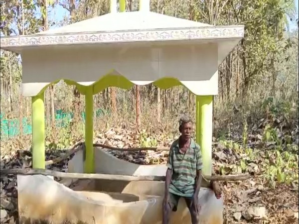 80-year-old Laxman Bhuyan sitting besides the grave he built for himself and his wife.