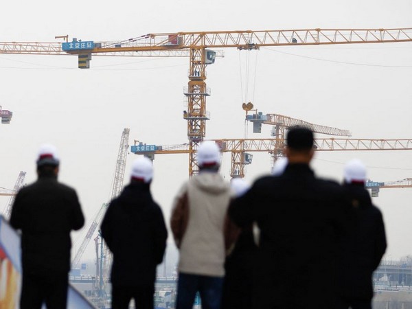People look on near cranes standing at a construction site in Beijing. (Photo Credit - Reuters)