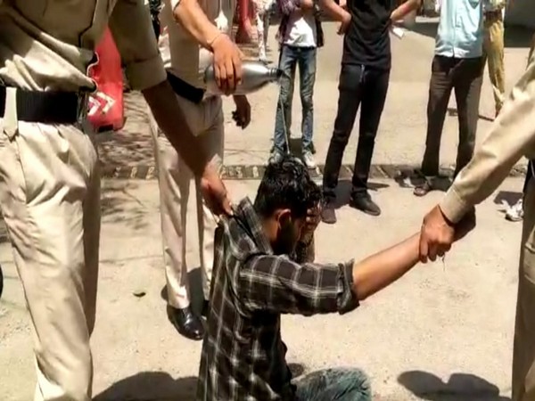 Police pouring water on the youth to clean inflammable substance (Photo/ANI)