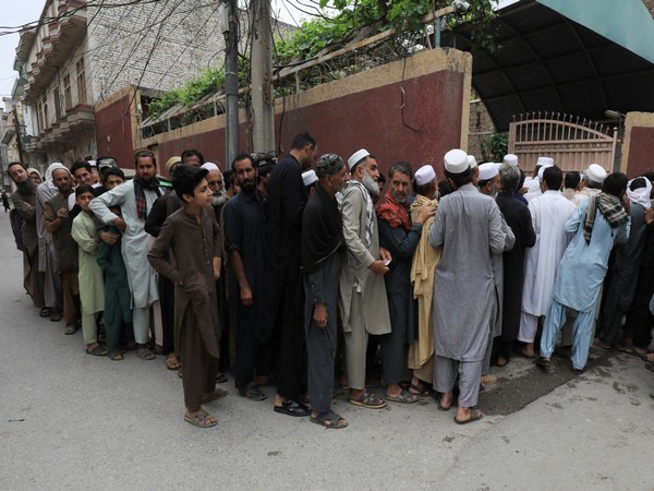 People stand in queue to receive sacks of free flour, at a distribution point in Peshawar, Pakistan March 30, 2023. (Photo/Reuters)