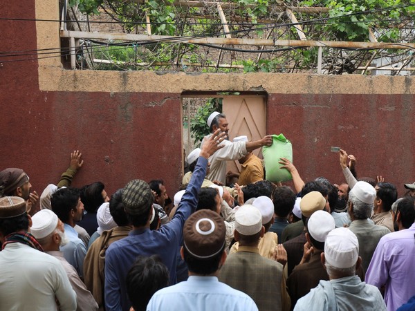 People gather to receive sacks of free flour at a distribution point in Peshawar, Pakistan March 30. (Photo/Reuters)
