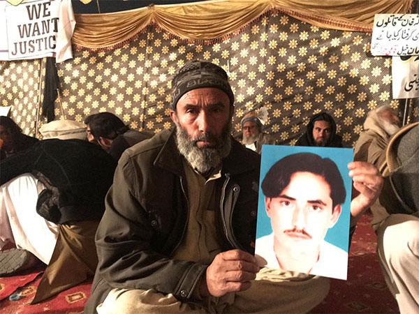 Mohammad Bilal holds son Hazratullah's picture, as he takes part in a protest against enforced 
