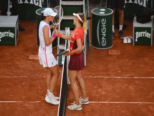 Iga Swiatek (in white) and  Lesia Tsurenko (in orange) shaking hands after the match (Twitter: Photo/RolandGarros)