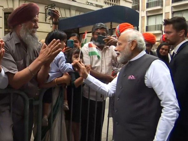 PM Narendra Modi greets a kid as he is welcomed by Indian community in Paris. (Photo/ANI)