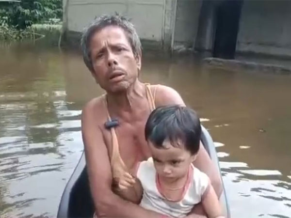 A local outside his submerged house in Assam (Photo/ANI)