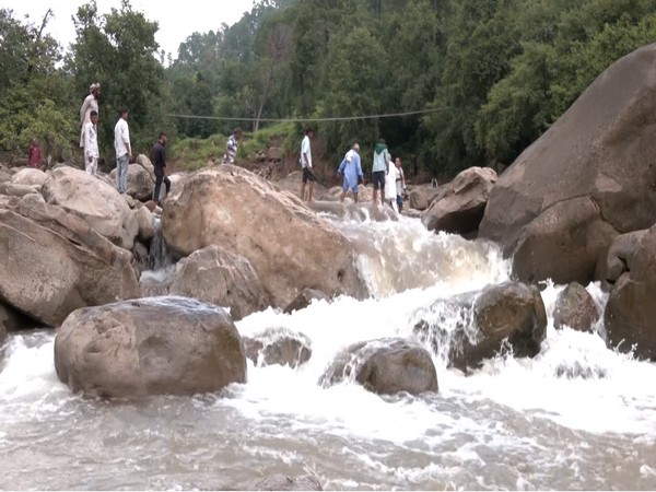 People forced to risk their lives to cross Nallah after a footbridge was damaged due to a flash flood triggered by recent rainfall in J&K’s Udhampur (Photo/ANI)