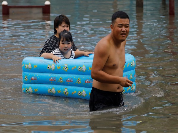 People make their way through floodwaters in Zhuozhou, Hebei province, China August 3, 2023. (Photo/Reuters)