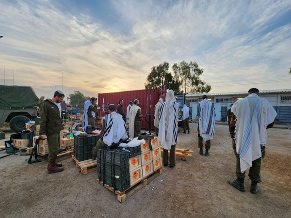 Israeli army reservists called up for duty say morning prayers at a muster point (Photo/TPS)