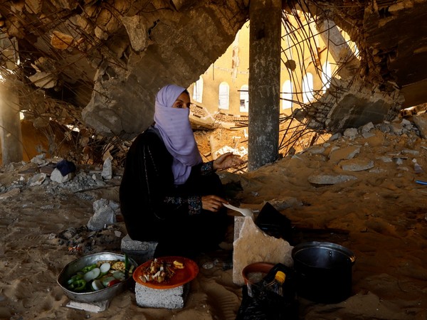 A woman cooks in a destroyed mosque, amid shortages of food supplies and fuel in Khan Younis (Photo Credit: Reuters)