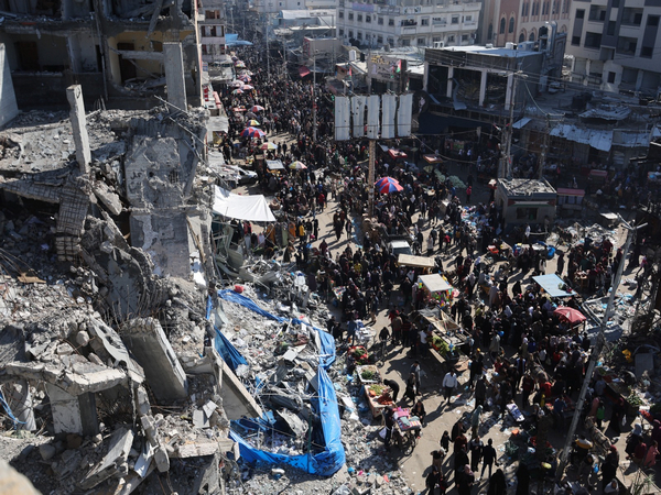 Palestinians shop near the ruins of houses and buildings destroyed in Israeli strikes during the conflict (Photo Credit: Reuters)