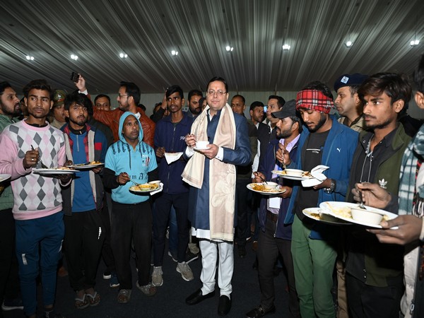 CM Pushkar Singh Dhami with workers associated with the arrangements of the Global Investors Summit. (Photo/ANI)