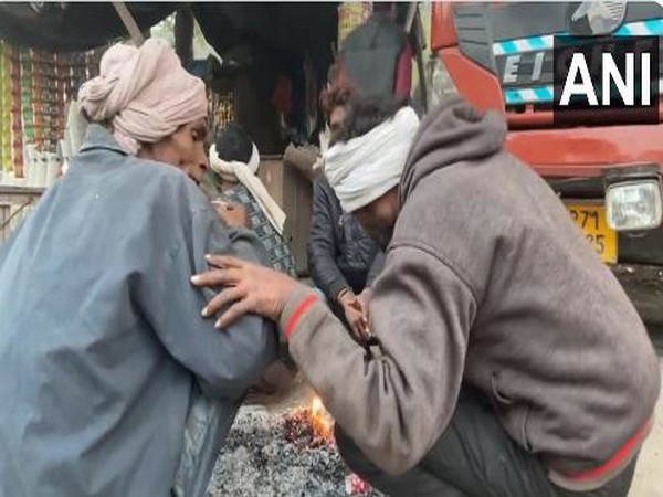 People huddled around a bonfire to ward off the cold. (Photo/ANI)