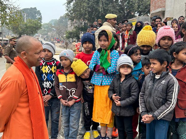 CM Yogi interacts with the children of PM Awas Yojana beneficiaries. (Photo/ANI)