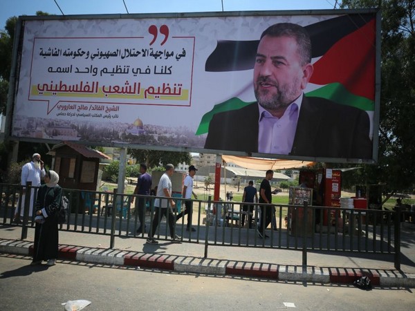 Palestinians in Gaza City walk past a billboard bearing a picture prominent Hamas terror commander of Saleh Arouri (Photo/TPS)