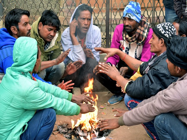 People sit in front of a bonfire during a cold morning in Rajasthan (Photo/ANI)