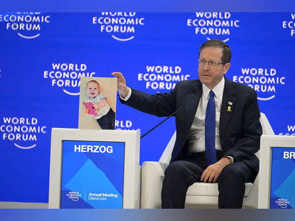 Israeli President Isaac Herzog displays a photo of one-year-old hostage Kfir Bibas at the World Economic Forum in Davos, Switzerland (Photo/TPS)