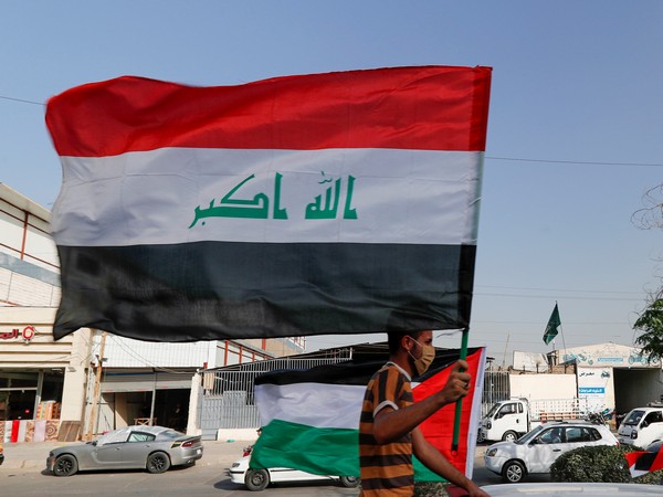 A member of Kataib Hezbollah paramilitary group holds an Iraqi flag (Photo/Reuters)