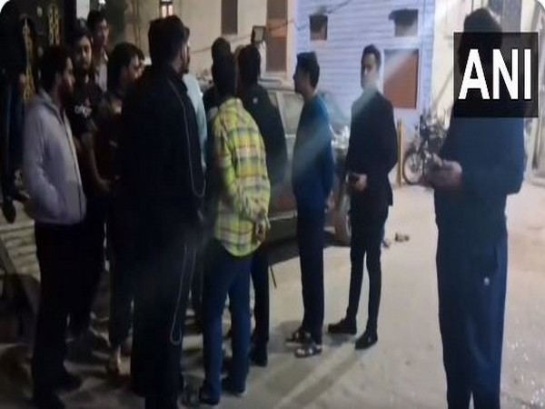Locals gather after multiple rounds were fired outside a house in Yamuna Vihar (Photo/ANI)