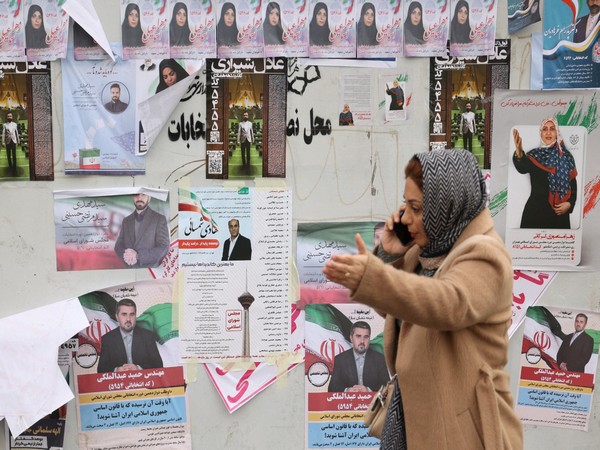 An Iranian woman walks past campaign posters for the parliamentary election in Tehran (Photo/Reuters)