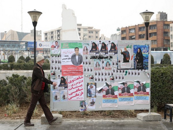 An Iranian man walks past campaign posters for the parliamentary election in Tehran (Photo/Reuters)