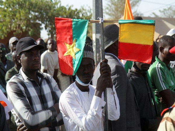 A man holds Mali and Burkina Faso flags while attending a sit-in in Niamey (Photo/Reuters)