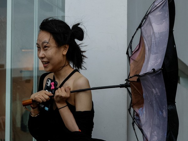 A woman struggles with an umbrella while walking against strong wind in China (Photo/Reuters)