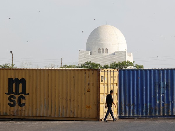 A man walks past shipping containers, used to block the area for security measures, following the visit of the Iranian President Ebrahim Raisi, in Karachi (Photo/Reuters)