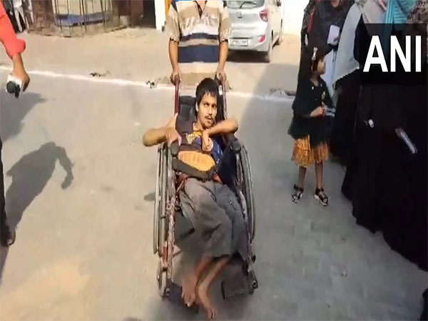 Specially-abled voter arrives in wheelchair at polling booth in UP's Kasganj. (Photo/ANI)