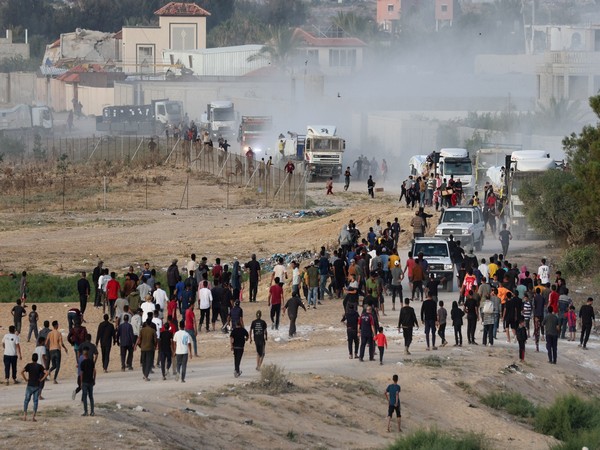 Palestinians walk towards trucks transporting aid that was delivered into Gaza through a U.S.-built pier, as seen from central Gaza Strip (Photo/Reuters)