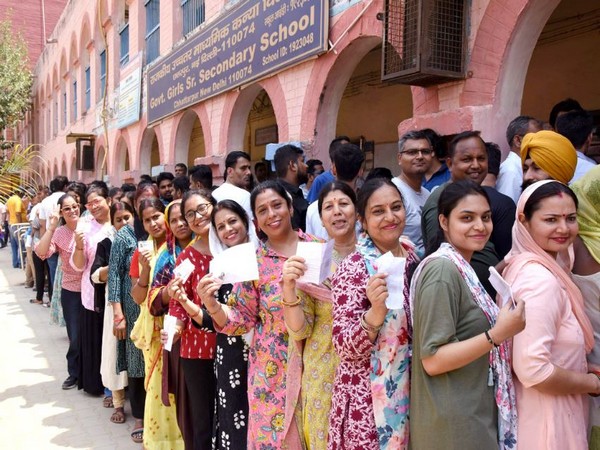 Voters display identity cards while standing in queue to cast their votes in New Delhi. (Photo/ANI)