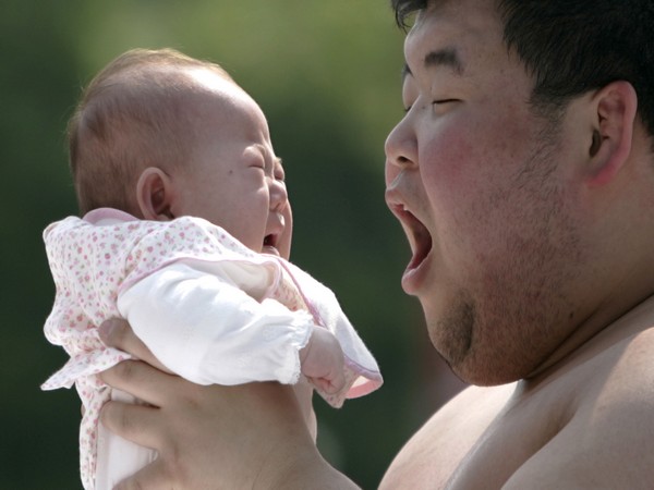 A baby cries as an amateur sumo wrestler tries to scare her during a baby crying contest in Tokyo (Photo/Reuters)