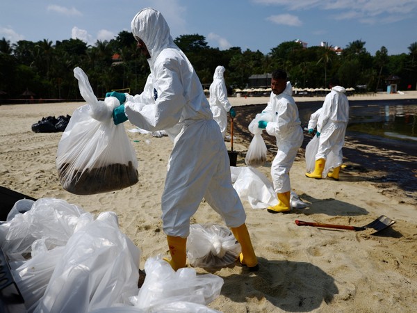 Workers clean up an an oil slick at Tanjong Beach in Singapore's Sentosa (Image Credit/ Reuters)