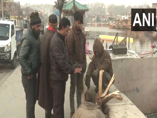 People light fire to keep warm in Srinagar (Photo/ANI)