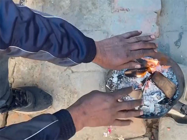 Visuals of a man keeping warm by a bonfire (Photo/ANI) 
