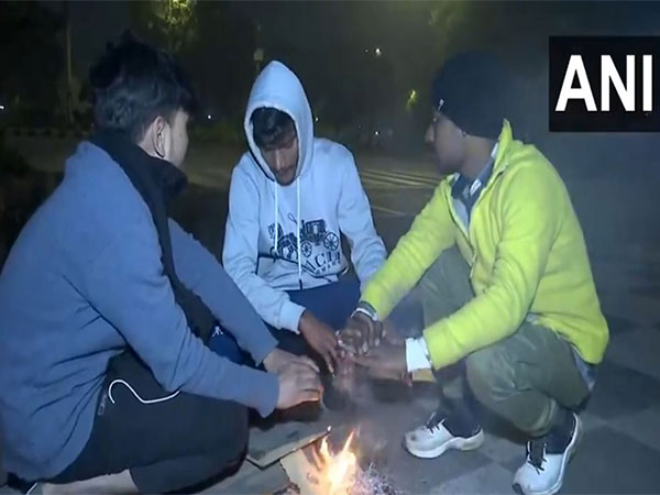 Residents take the help of a bonfire to keep themselves warm as mercury dips in the National Capital. (Photo/ANI)