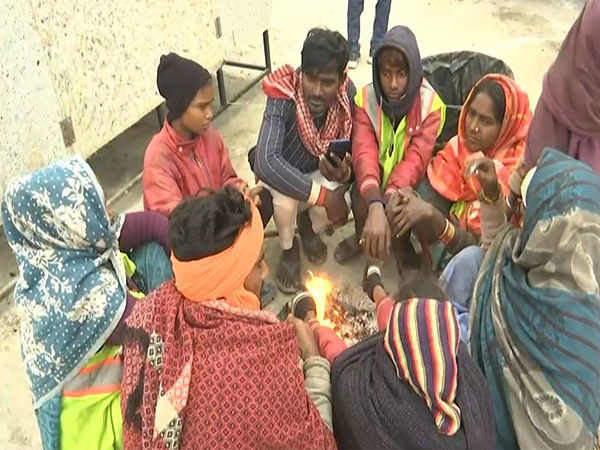 Devotees warm themselves near a bonfire in Prayagraj (Photo/ANI)